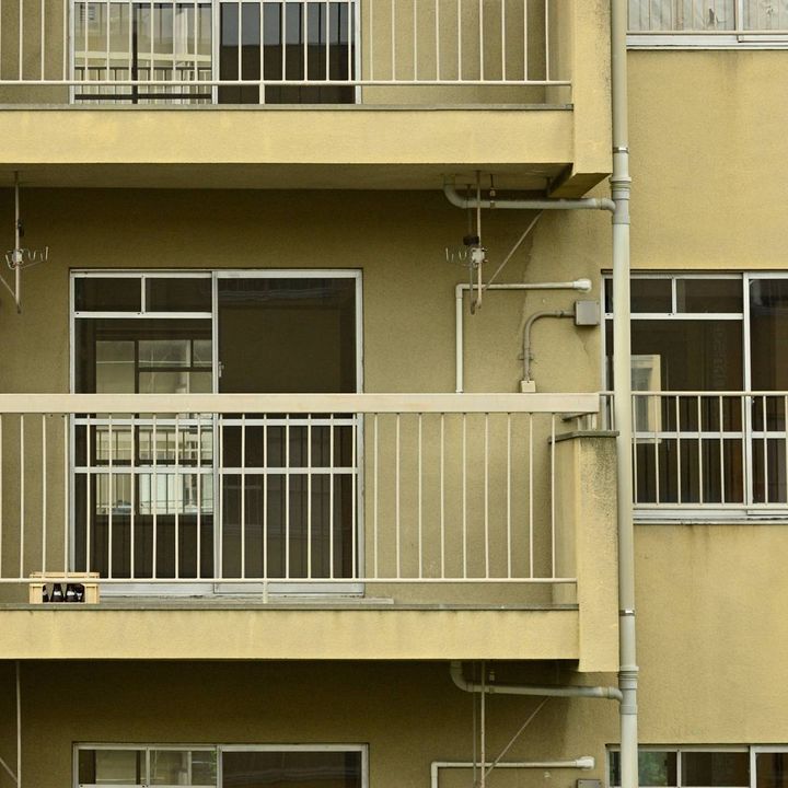 団地のベランダ。手すりのそばに小さな子ども用の踏み台が置かれている。