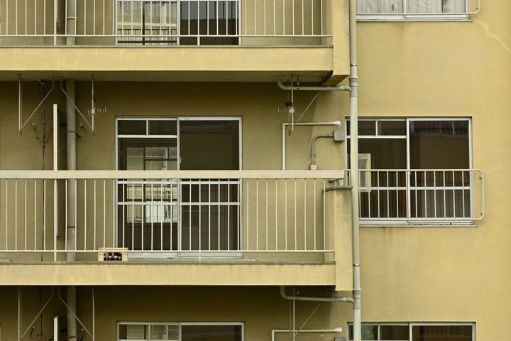 団地のベランダ。手すりのそばに小さな子ども用の踏み台が置かれている。