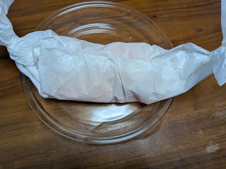 5、クッキングシートをキャンディ包みにする。耐熱容器にのせる。