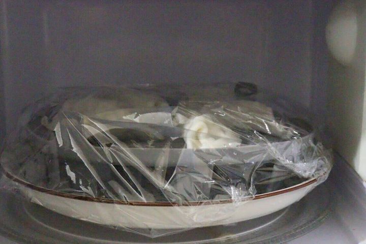 電子レンジの中でラップをかけた皿に蒸し器が入っている様子