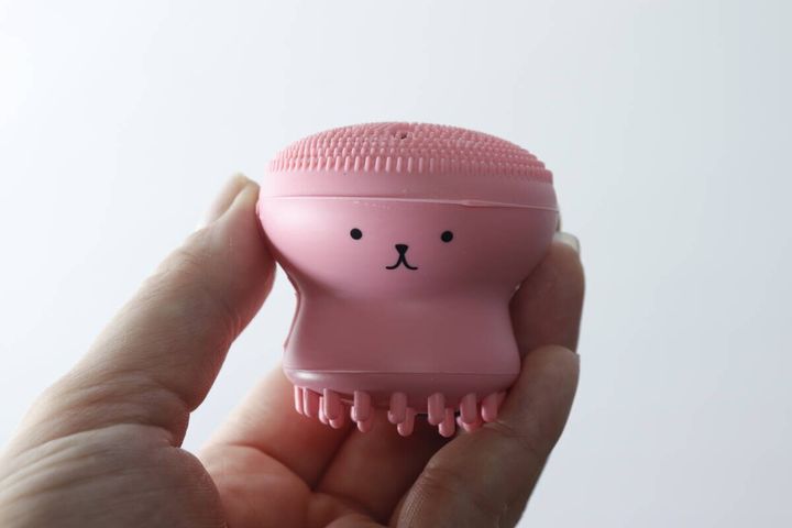 女性の手に持たれたピンク色の洗顔ブラシ。うさぎの顔が描かれている
