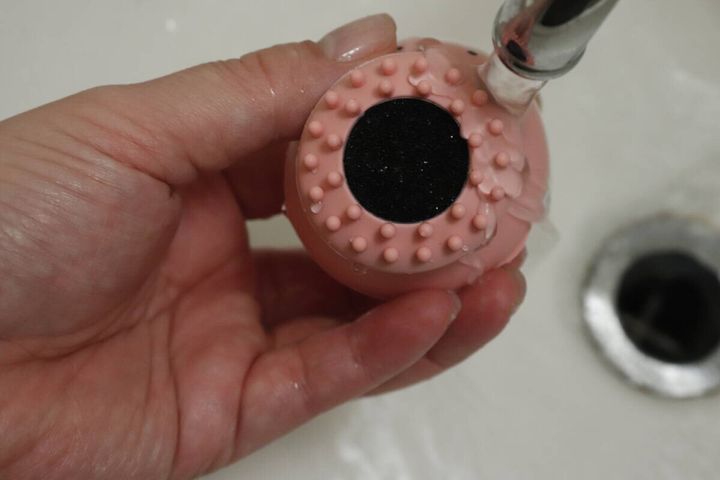 洗顔ブラシの底面に水道の蛇口から水がかけられている様子