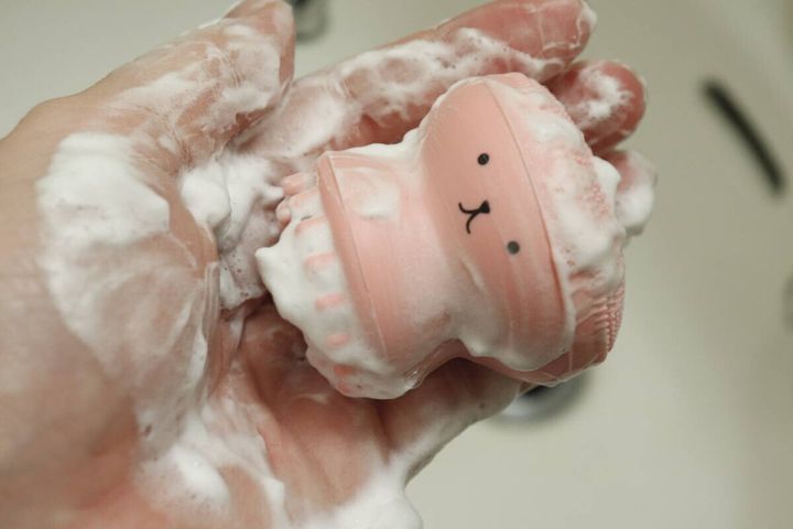 泡立った洗顔ブラシを女性が手に持ち、うさぎの顔が見える