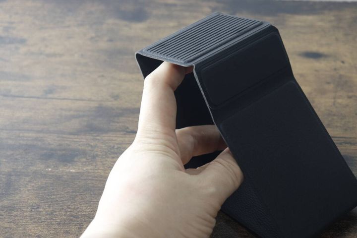 黒いスマホスタンドを開き始める手のアップ