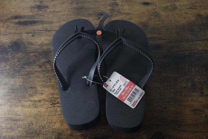 木目のテーブルに置かれた黒い厚底ビーチサンダルと商品タグ