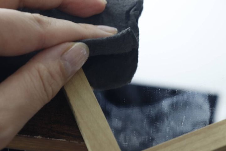 汚れた鏡の一部をグレーのクロスで拭いている手元