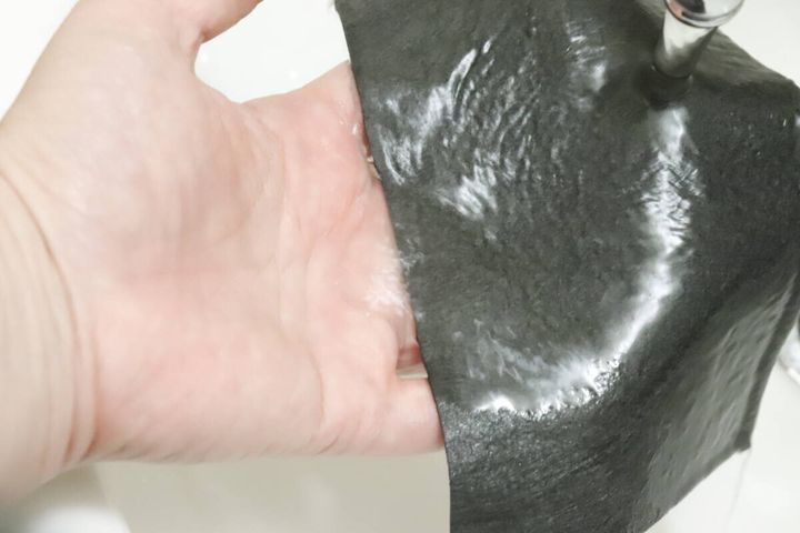 手でマイクロファイバークロスを水で濡らしている様子