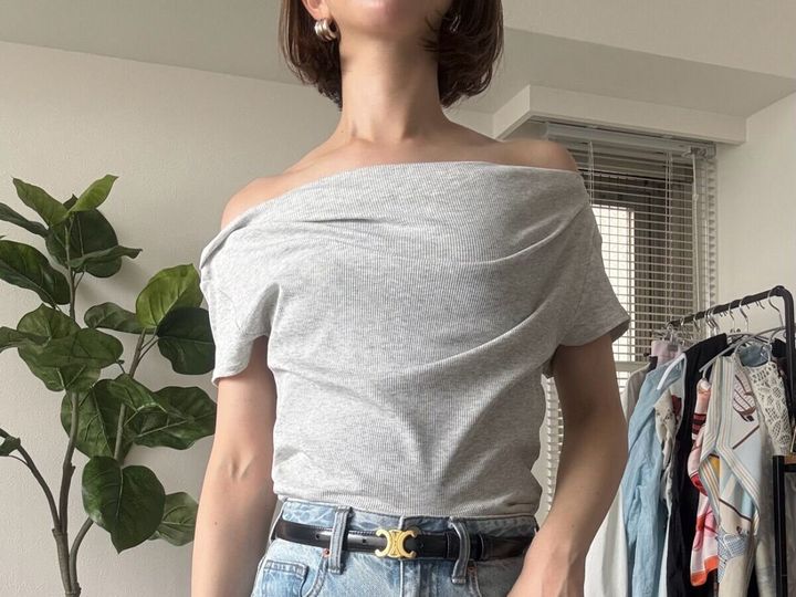 女性がグレーのドレープネックTをオフショルダーで着用