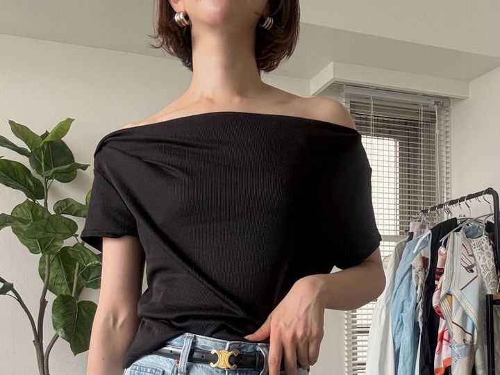 女性が黒のドレープネックTをオフショルダーで着用