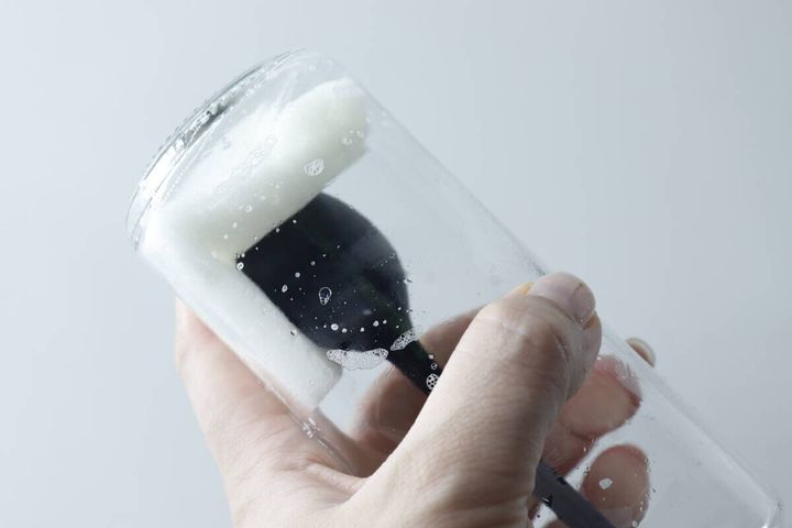 オイルボトルを使い捨てスポンジで洗っている手の様子