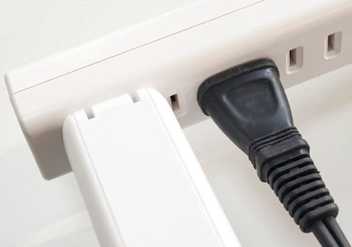 白い延長コードに大きなアダプターと黒いプラグが挿さっている