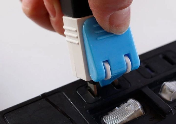 手が青い電源アダプターを電源タップに差し込んでいる