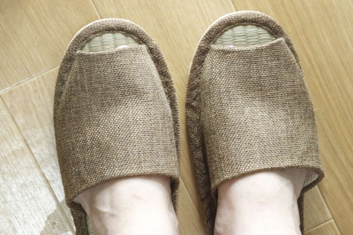 フローリングの上で、い草スリッパを素足で履いている足元