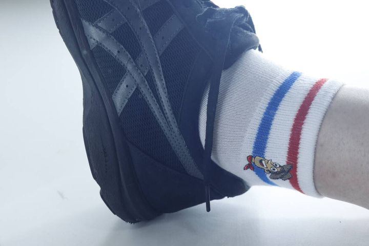 黒いスニーカーとウッディの靴下を履いた足元