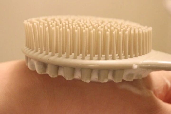 柄付ボディブラシのソフトな面を腕に当てている