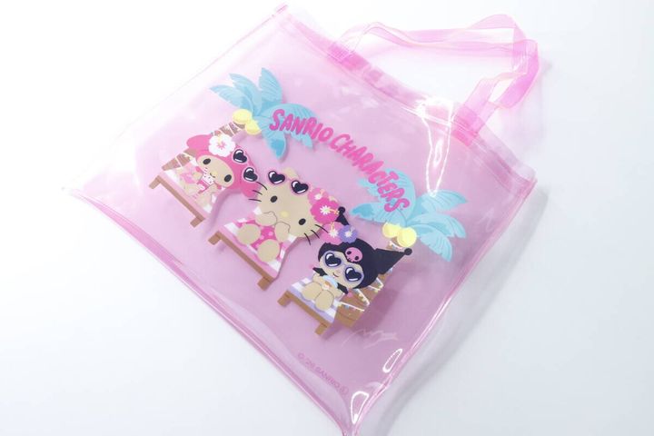 ピンク色の透明なPVCバッグが平置きされており、日焼けしたサンリオキャラクターが描かれている