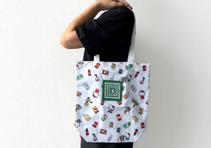 黒い服を着た人が白地の紀ノ国屋×ハローキティ保冷・保温バッグを肩にかけている