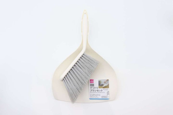 白い背景に、ベージュ色のミニチリトリとブラシが重なって置かれている。チリトリには商品ラベルが見える。