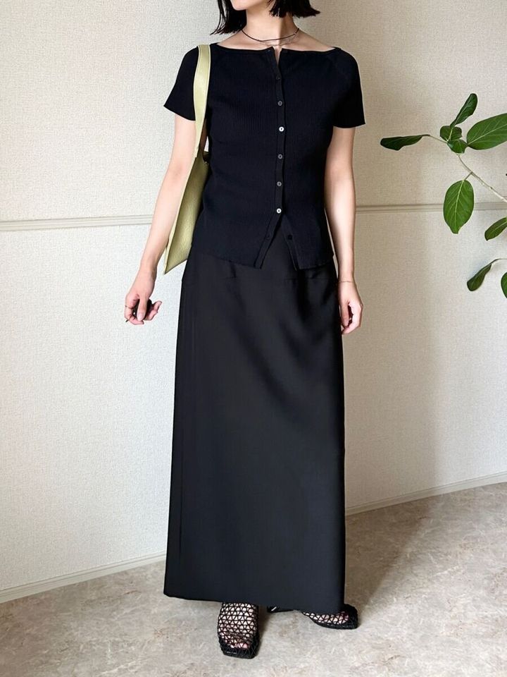 黒カーデと黒ロングスカート、緑バッグの女性