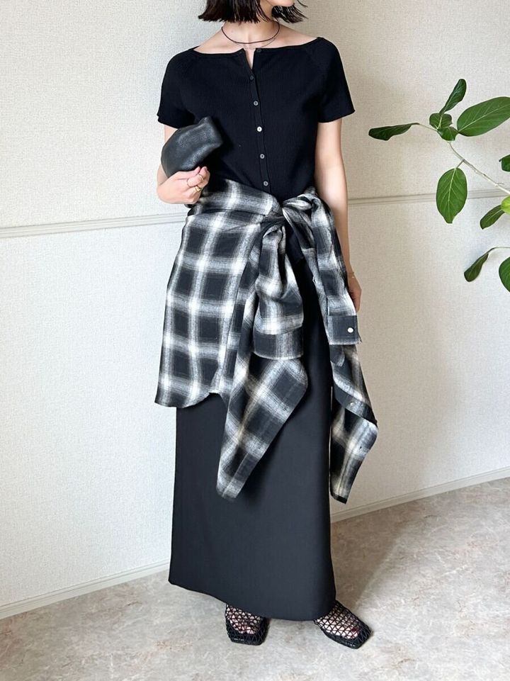 黒カーデと黒スカートにチェックシャツを腰巻きした女性