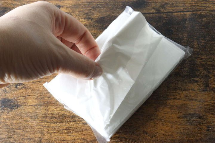 手がコンパクトなレジ袋の束から一枚取り出そうとしている様子