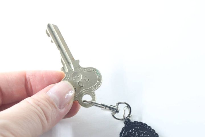 キーホルダーの金具に鍵を取り付けている手元をクローズアップ