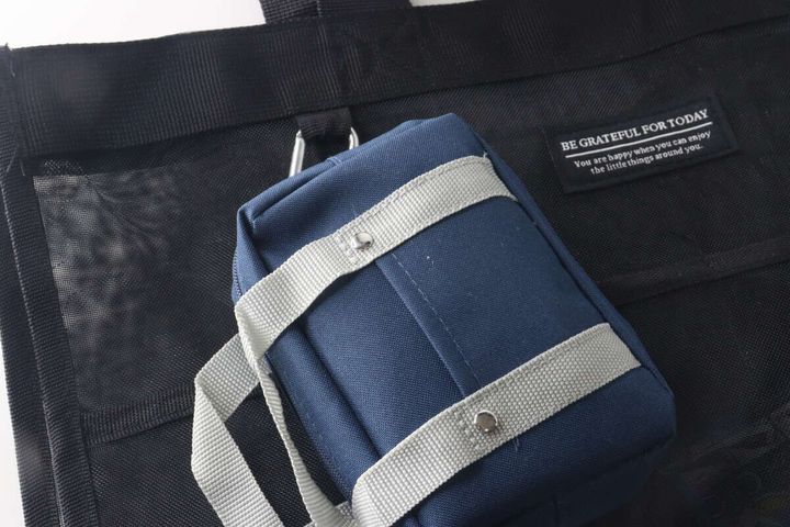 黒いトートバッグにネイビーのミニスクールバッグ型ポーチをカラビナで付けている様子