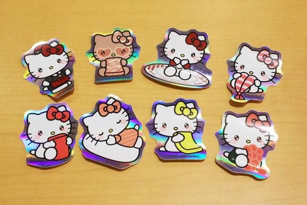 「第1弾 ハローキティ コラボステッカー付き りんごのミルクレープメルバ」(350円〜)に付属するコラボステッカーは全部で8種類。キラキラ輝く背景もキュート！
