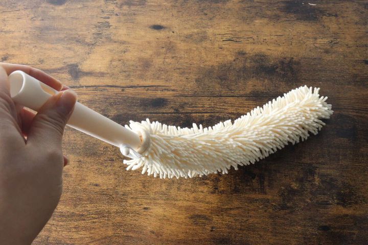 手で持ったハンディモップのモップ部分がしなっている様子