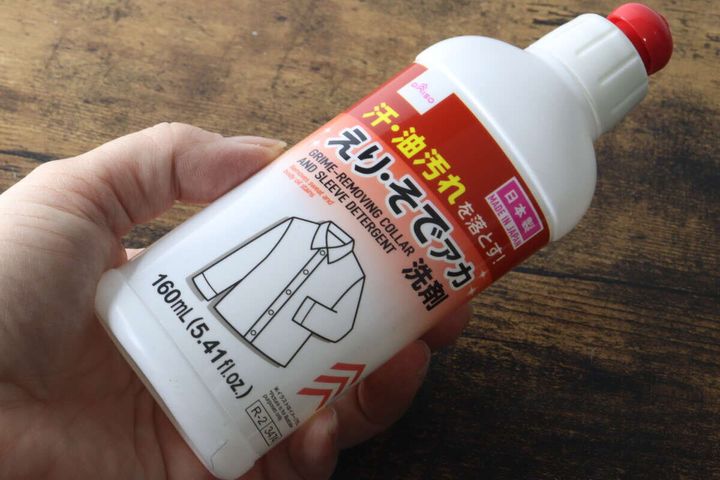 手で「えり・そでアカ洗剤」のボトルを握っている様子
