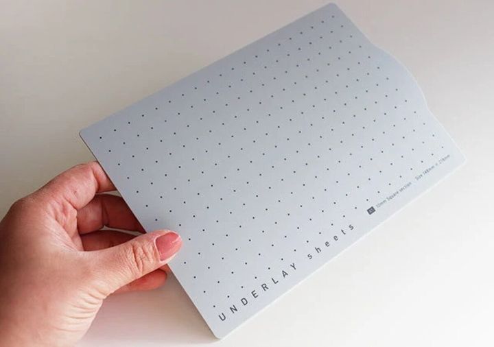 女性の手がドット模様のグレーのA5サイズ下敷きを持っている