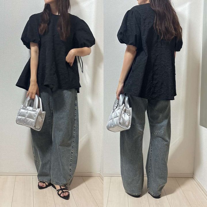 黒いパフスリーブブラウスとバレルジーンズの女性