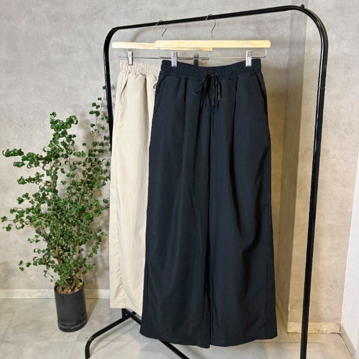 ハンガーラックに掛かるベージュと黒のワイドパンツ