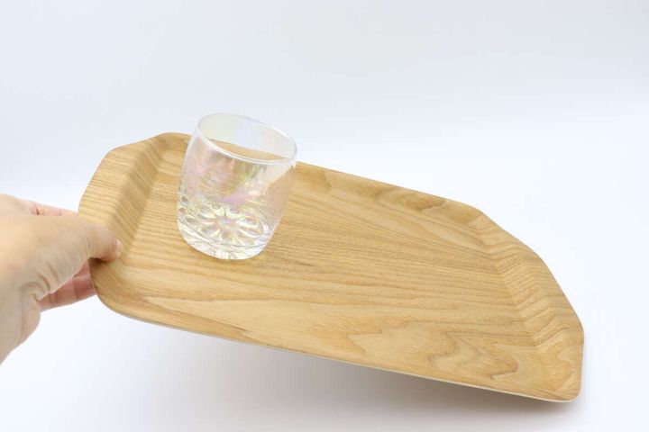 手で傾けたトレーにガラスコップが安定している様子
