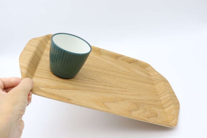 手で傾けたトレーにプラスチックコップが安定している様子