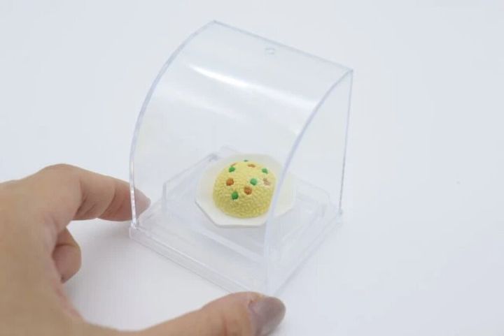 女性の手がミニチュアフードディスプレイにチャーハンのミニチュアを置いている