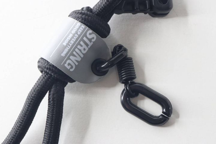 キーホルダー中央の「STRING」ロゴタグと下部のカラビナのアップ