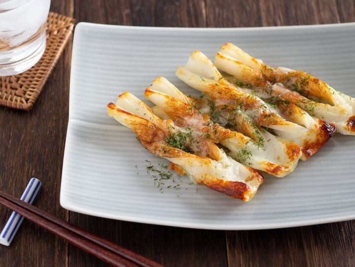 ねじったちくわにチーズと青のりをのせて焼いたものが白い皿に4本並んでいる