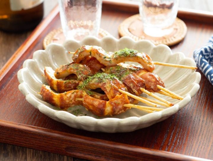 マヨソースで炒めたちくわを串に刺し青のりをかけた料理が花形の白い皿に盛られている