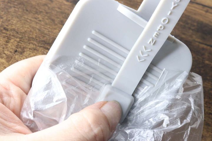 シリコーンケースの裏面にある凹凸部分でレジ袋の口をこすって開けている手元
