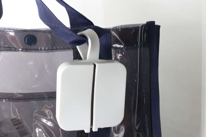 白いシリコーンレジ袋ケースを透明なバッグの持ち手に吊り下げて携帯している様子