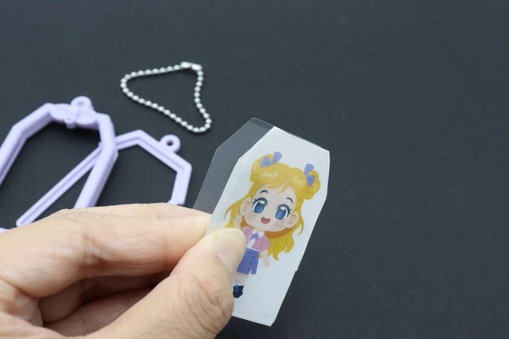 切り抜いたイラストを透明シートで挟んでいる手元