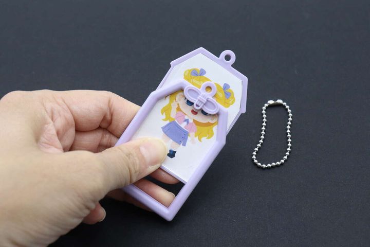 透明シートで挟んだイラストを紫色の内フレームにセットしている手元