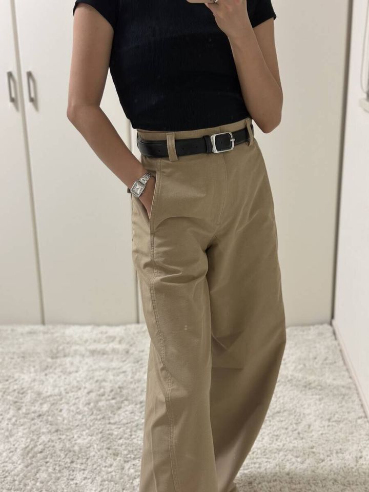 黒トップスとベージュパンツの女性がポケットに手を入れている
