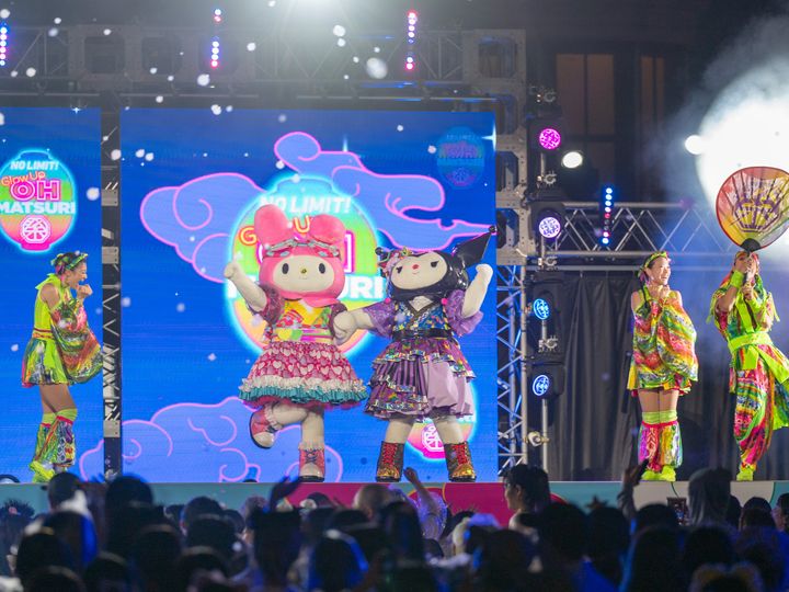 Glow Up OH MATSURIと書かれた大団扇を掲げる出演者