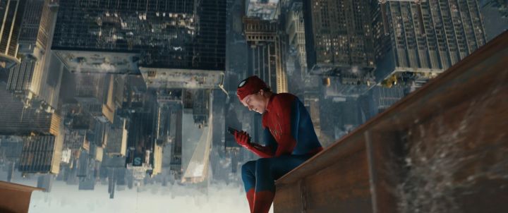 高層ビルの縁に腰かけてスマートフォンを見るスパイダーマン