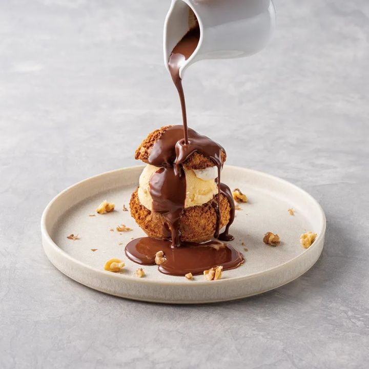 チョコレートソースをかけるプロフィットロール