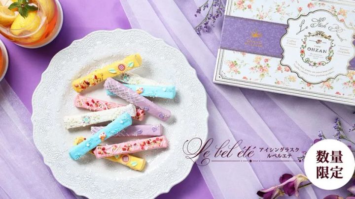 紫の布を背景に、花火やひまわりなどで彩られたカラフルなスティックラスクとCAFE