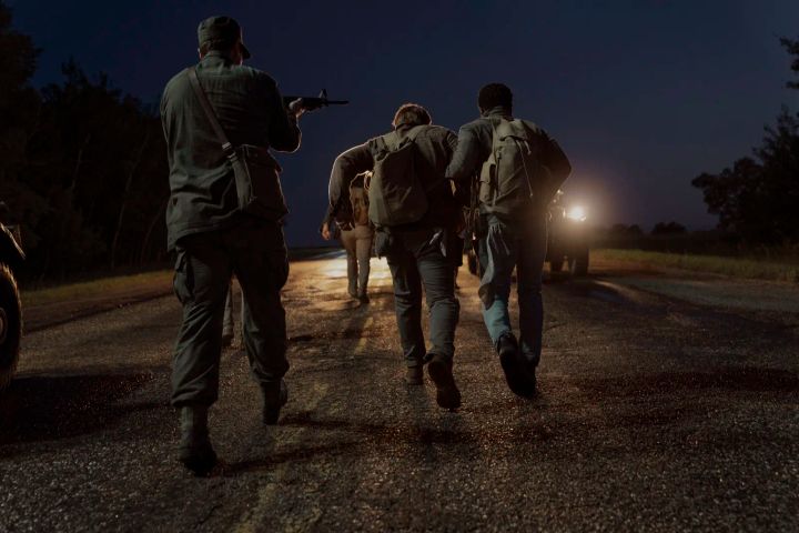 銃を構えた兵士に見張られながら夜道を歩く『ロングウォーク』の参加者