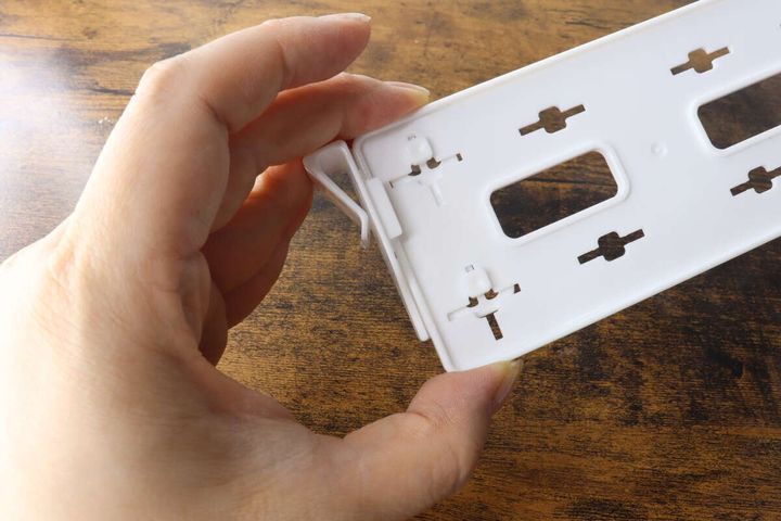 白い仕切り板のフックを上下にスライドさせている手元